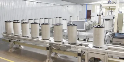 Automated conveyor system transporting finished heavy duty air filter cartridges ready for final packaging.