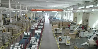 Expansive metalworking workshop featuring large inventory of raw steel coils ready for heavy duty filter casing production.